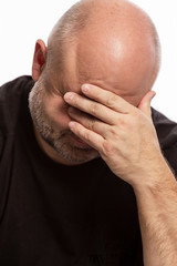 Fototapeta premium A bald man thinks covered his face with his hands, close-up