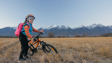 One caucasian children walk with bike in wheat field. Little girl walking black orange cycle on...