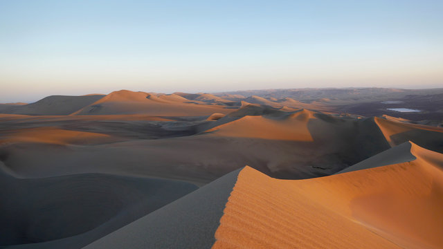 Huacachina is a desert oasis in the sand dunes of Peru. It's 6pm and I'am sitting atop a giant wind-sculpted sand dune watching the sun set.