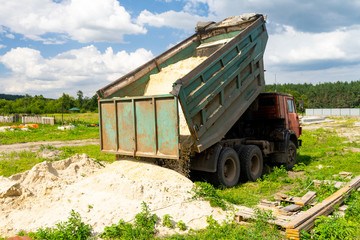The dump truck unloads sand. The truck dumped the cargo. Sand and gravel. Construction site, materials warehouse.