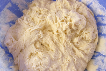 Preparation of yeast dough in a blue plastic bowl. Close-up view.