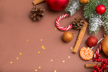 Obraz na płótnie Canvas spruce branch, Golden, red Christmas balls, cones, cinnamon sticks, sweets on a brown background