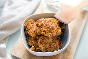 pancakes from carrots and apples in a plate, a wooden kitchen shovel, vegetable pancakes
