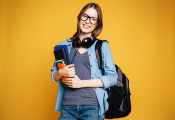 Happy and excited cute young student girl portrait in glasses with backpack isolated in studio