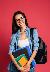 Happy and excited cute young student girl portrait in glasses with backpack isolated in studio