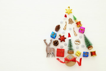 Top view image of festive decorations in shape of christmas tree over white wooden background. Flat lay.