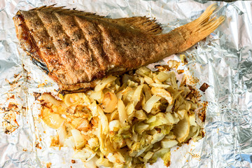 fish baked with vegetables lies in a foil