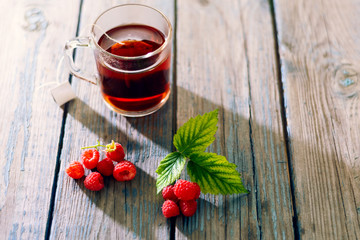 tea with ripe raspberries and green fresh brewed leaves healthy for health on a wooden table