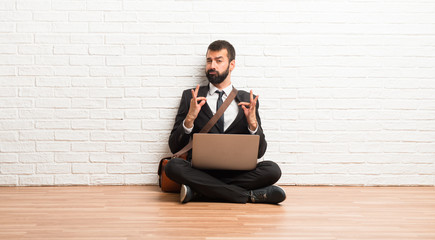 Businessman with his laptop sitting on the floor proud and self-satisfied in love yourself concept