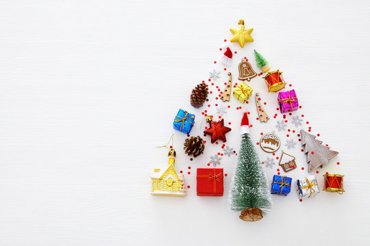 Top view image of festive decorations in shape of christmas tree over white wooden background. Flat lay.