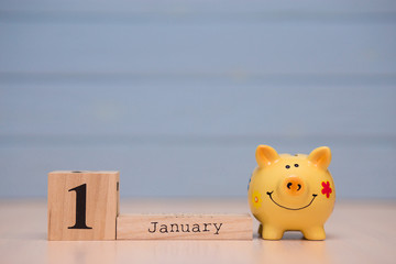 Calendar date of Financial Year start, 1st january with piggy bank on blue background. Winter time.