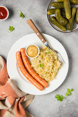 Braised white cabbage with two long fried sausages, mustard and pickled cucumbers. Classic German Hungarian Bavarian food