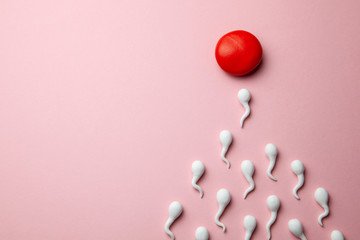 Active sperm cells swim to the egg on a pink background. The concept of pregnancy, fertilization of...