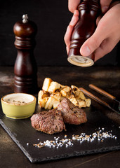 Two steak filet Mignon with side dish of baked potatoes and celery, with salt and pepper. Beautiful restaurant serving