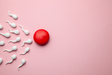 Active sperm cells swim to the egg on a pink background. The concept of pregnancy, fertilization of...