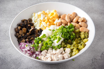 Cooking russian salad with meat, potatoes, egg, cucumber, beans, onion, mushrooms and mayonnaise