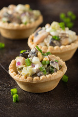 Russian salad with meat and beans in tartlet. With potatoes, egg, cucumber, onion, mushrooms and mayonnaise. Delicious appetizer for wine buffet
