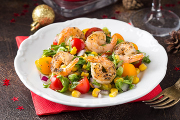 Salad with corn, fried shrimp, cherry tomatoes, red onions and lettuce on white plate. Appetizer for Christmas party