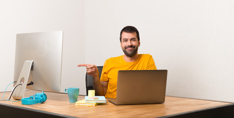 Man working with laptot in a office pointing finger to the side in lateral position