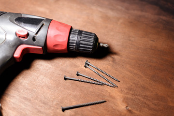 electric screwdriver and screws lie on a wooden table