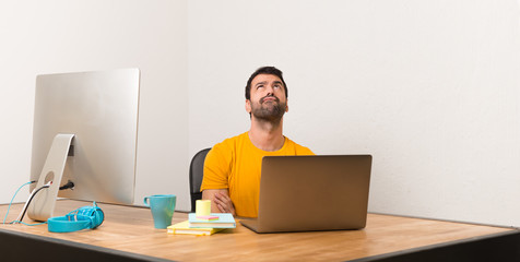 Man working with laptot in a office looking up with serious face