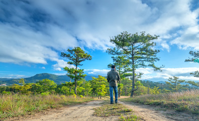 Man walking on the dirt road along the hillside pine forest discovery journey during his travels