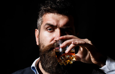 Sipping whiskey. Portrait of man with thick beard. Macho drinking. Degustation, tasting. Man with beard holds glass brandy. Bearded drink cognac. Sommelier tastes drink. Man holding a glass of whisky