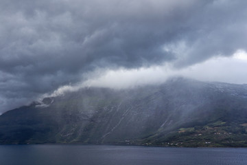 Wolken regnen sich auf anderer Fjordseite ab