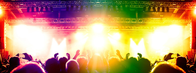 Concert crowd clapping in front of a big stage