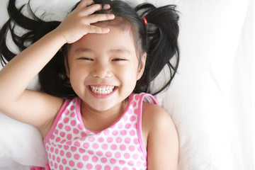 Asian child happy or kid girl smiling and open eye sleep or wake up for relax on white bed with...