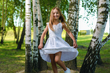 pretty little girl in white dress whirls and dances among the trees