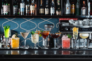 row of various colourfull alcoholic cocktails on a bar desk. Glasses of differen shapes