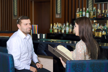 man in white shirt is looking at beautiful santa girl in black dress.