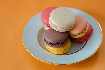 Colorful macaroons are on the orange background,