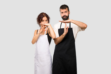 Couple of cooks making stop gesture with her hand to stop an act on grey background