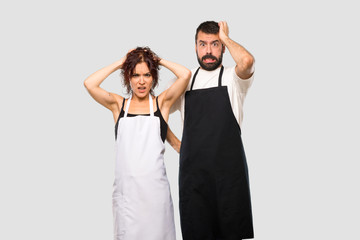 Couple of cooks takes hands on head because has migraine on grey background