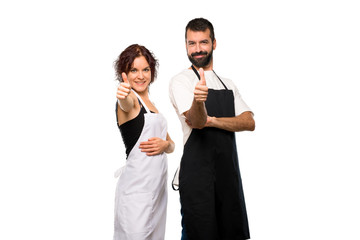 Couple of cooks giving a thumbs up gesture and smiling on isolated white background