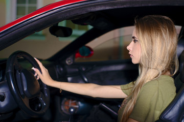 Fototapeta na wymiar young blond girl in the evening driving a sports car