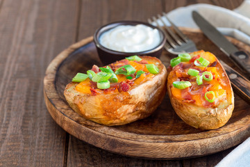 Baked loaded potato skins with cheddar cheese and bacon, garnished with scallions and sour cream, horizontal, copy space
