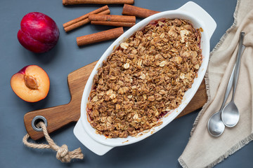 Plum crumble pie or plum crisp with oats and spices, in a baking dish, top view, horizontal