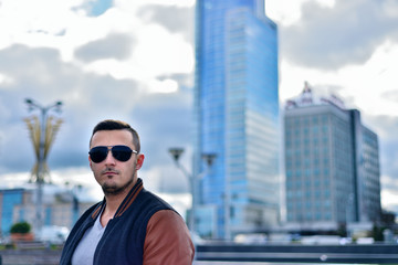 portrait of brutal man in sunglasses in the city on the background