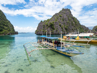 CORON, PHILIPPINES - November, 2018: Unidentified tourist and a traditional boats at the Barracuda lagoon in Coron island, Philippines