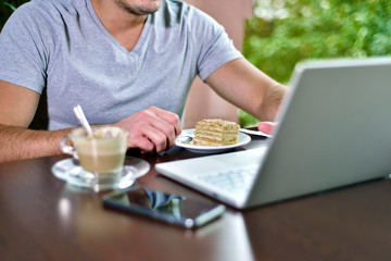 Young guy freelancer working on laptop in cafe