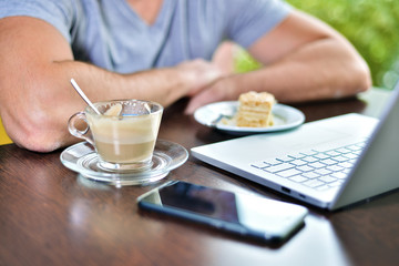 Young guy freelancer working on laptop in cafe