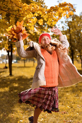 Obraz premium girl in red cap jumps with an autumn bouquet of leaves