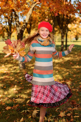 girl in red cap jumps with an autumn bouquet of leaves