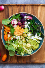 Buddha bowl with mixed roast and fresh vegetables, hummus and miso dressing