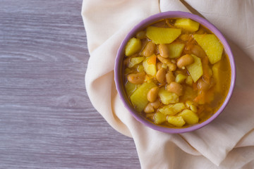 Photo bean soup in a plate on a light napkin and a wooden table.