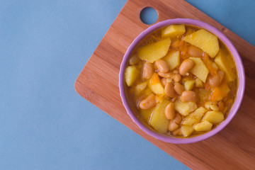 Photo bean soup in a plate and pieces of bread on a wooden Board on a blue background.