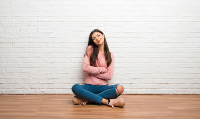 Teenager girl sitting on the floor in a room keeping the arms crossed in frontal position